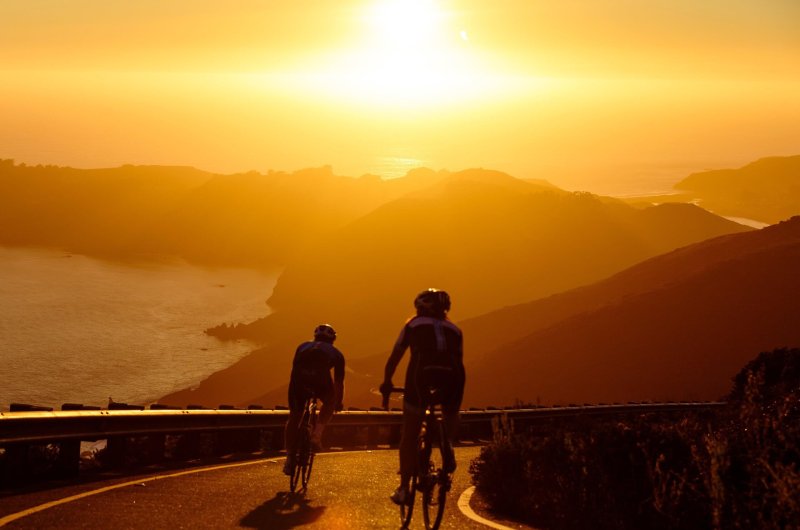 2 cyclistes roulant sur la côte méditéranéenne dans le couchant.