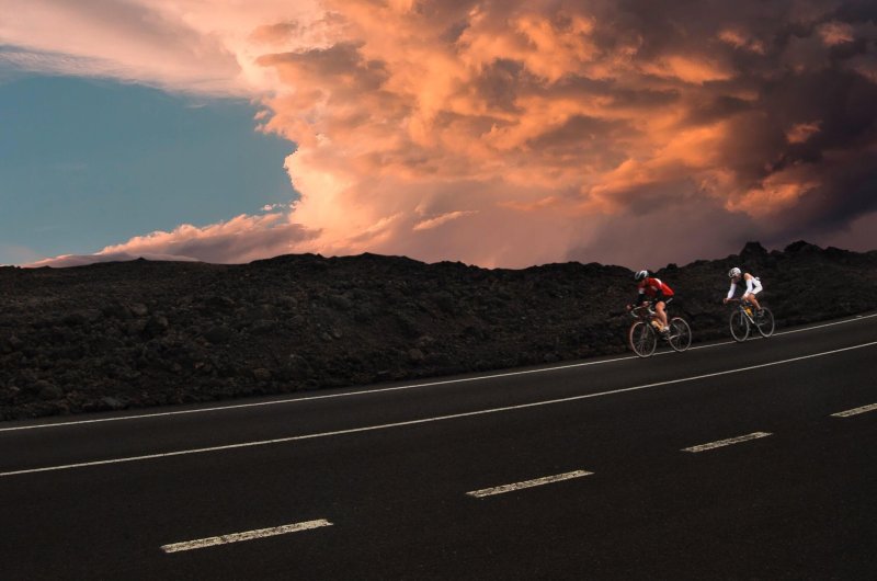 Duo de cyclistes roulant à vive allure sur une route dans le couchant.