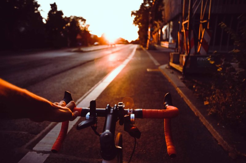 Une main sur un guidon de vélo de route dans le couchant.